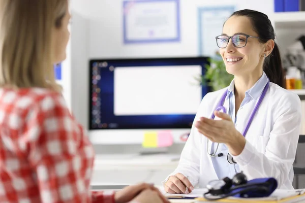 Lächelnder Arzt im Gespräch mit Patient am Tisch in Klinik — Stockfoto