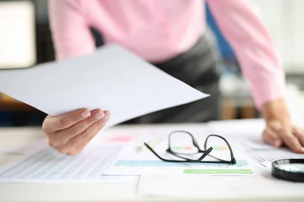 Weibliche Hände halten Dokumente auf dem Tisch, kommerzielle Diagramme und Lupe. — Stockfoto