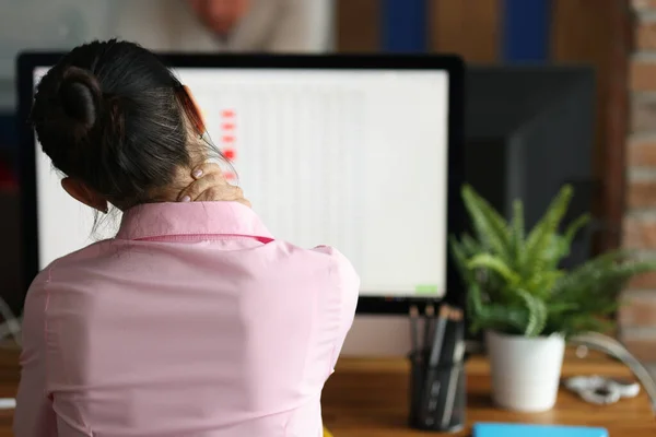 Unavená žena sedí u počítače a masíruje bolest v krku — Stock fotografie