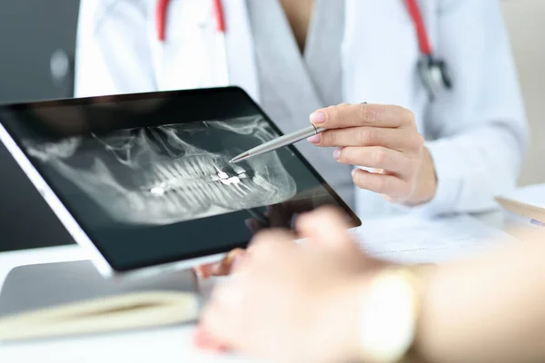 Tandläkare visar en röntgen av käken till patienten på tabletten. — Stockfoto