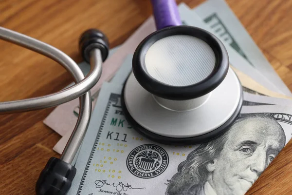 Dollar bills on table with stethoscope on them — Stock Photo, Image