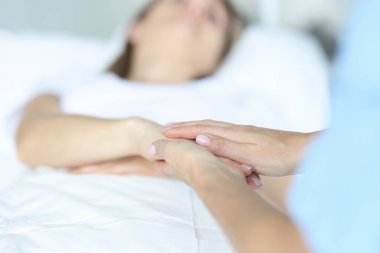 Doktor el ele tutuşup klinikte hasta hastayı sakinleştiriyor.