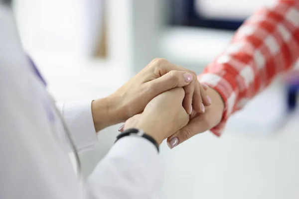 Doctor en bata blanca estrechando las manos con el paciente en primer plano de la clínica — Foto de Stock