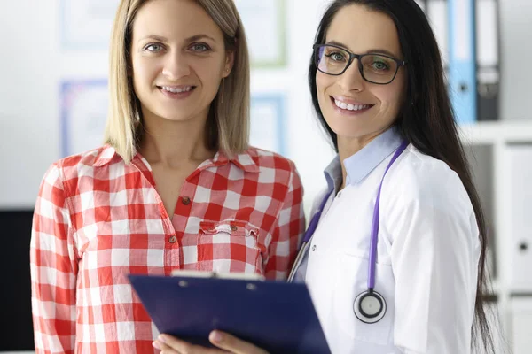 Smiling doctor and patient stand in clinic office — Stock Photo, Image