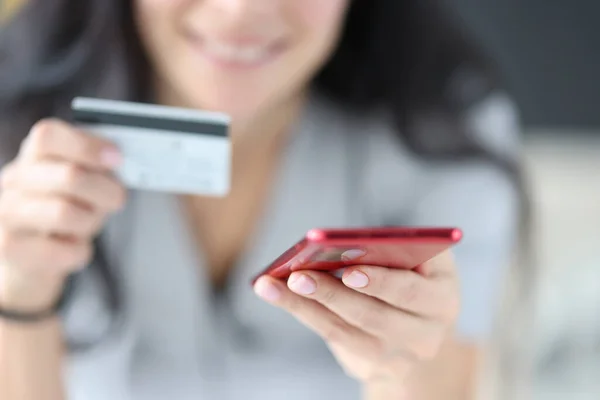 Mulher segurando cartão bancário e telefone em suas mãos close-up — Fotografia de Stock