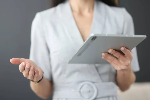 Zakelijke vrouw houdt tablet in handen en zwaait met haar hand in het kantoor — Stockfoto