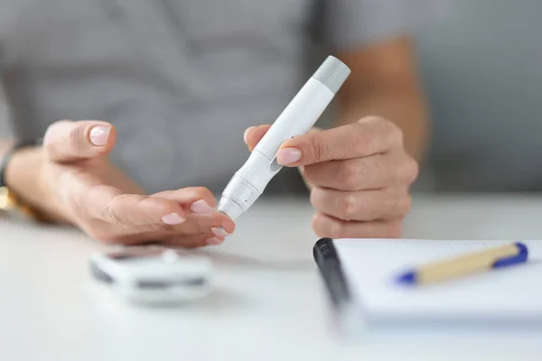 Frau hält Lanzette am Finger, um Blutzucker in Nahaufnahme zu messen — Stockfoto