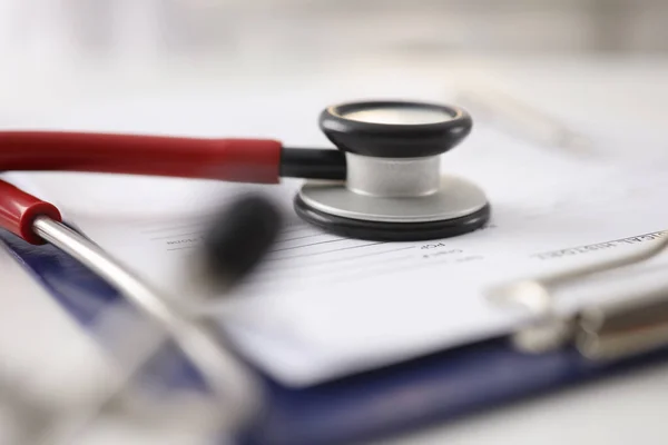 Czerwony stetoskop leżący na dokumentach w schowku w klinice zbliżenie — Zdjęcie stockowe