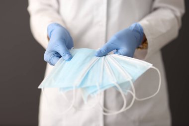 Plastik eldiven takan doktor birçok koruyucu yüz maskesi tutuyor.