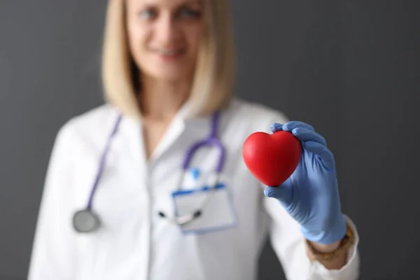 Läkare i gummihandskar håller röd leksak hjärta i händerna närbild — Stockfoto