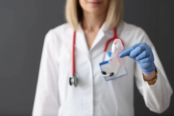 Läkaren håller rosa band i handen i gummi handske närbild — Stockfoto