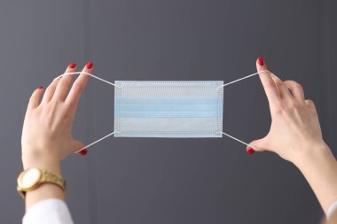 Koruyucu tıbbi maske tutan kadın elleri yakın plan.