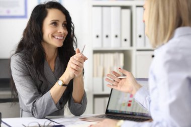 İş kadınları ofiste gülümsüyor ve konuşuyor.