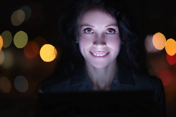 Portret van brunette vrouw op laptop 's nachts tegen de achtergrond van slingers — Stockfoto