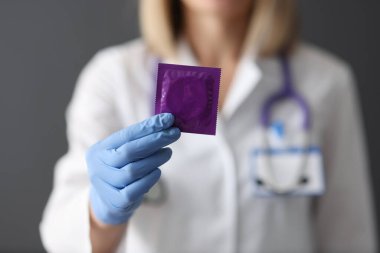 Doktor elinde prezervatif tutuyor.