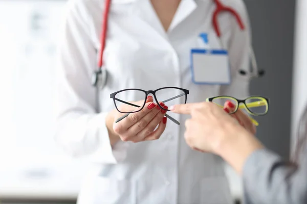 Офтальмолог показывает пациенту две пары оптики. — стоковое фото