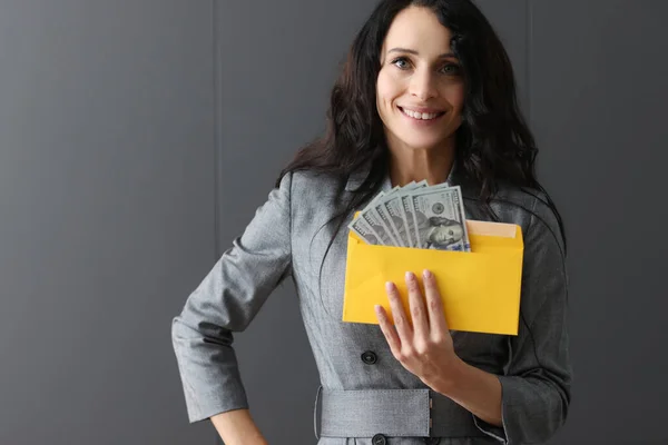 Mujer sonriente sosteniendo un sobre con dólares americanos. —  Fotos de Stock