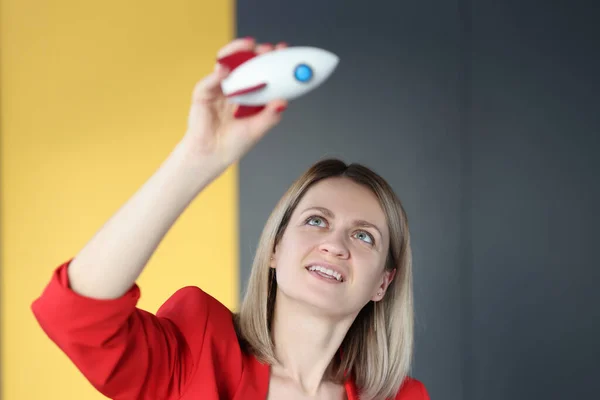 Vrouw in rood jasje houden speelgoed raket boven haar hoofd — Stockfoto