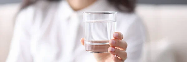 Mujer sostiene en su mano un vaso de agua transparente — Foto de Stock