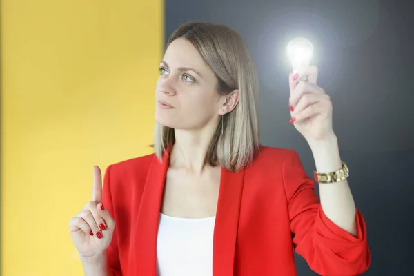 Pensive vrouw houdt gloeilamp in haar hand. — Stockfoto