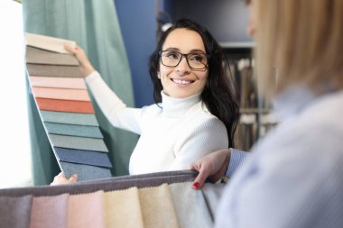 Satıcı perdeler için kumaş örnekleri gösterir