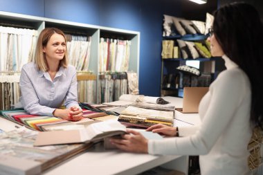 Kadın danışman, müşteriye atölyede perde seçmesinde yardım ediyor.
