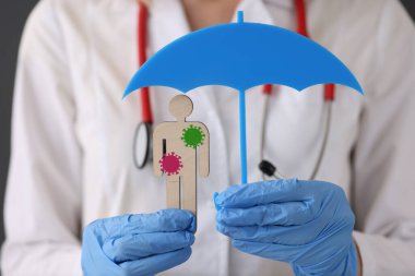 Kauçuk eldivenli doktor, elinde tahta oyuncakla şemsiye tutuyor.