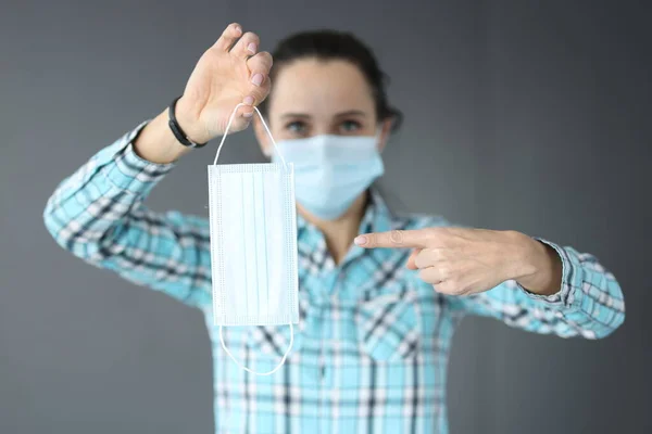 Kvinna i skyddande medicinsk mask håller en medicinsk mask i sina händer — Stockfoto