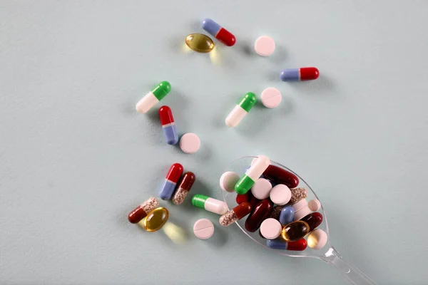 Há colher com comprimidos diferentes na mesa — Fotografia de Stock