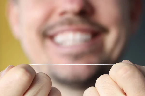 Smiling man holding dental floss in his hands — Stock Photo, Image