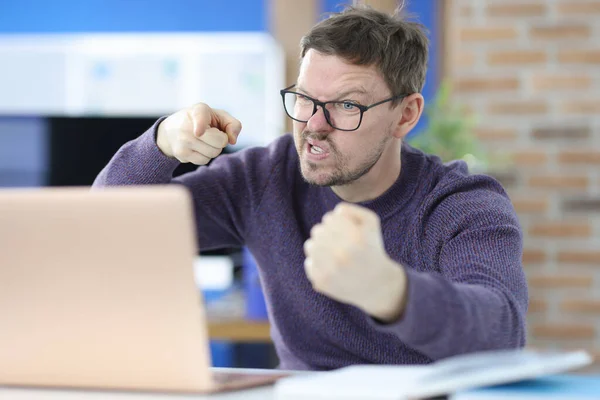 Angry man sits at work table in front of laptop — Stock Photo, Image