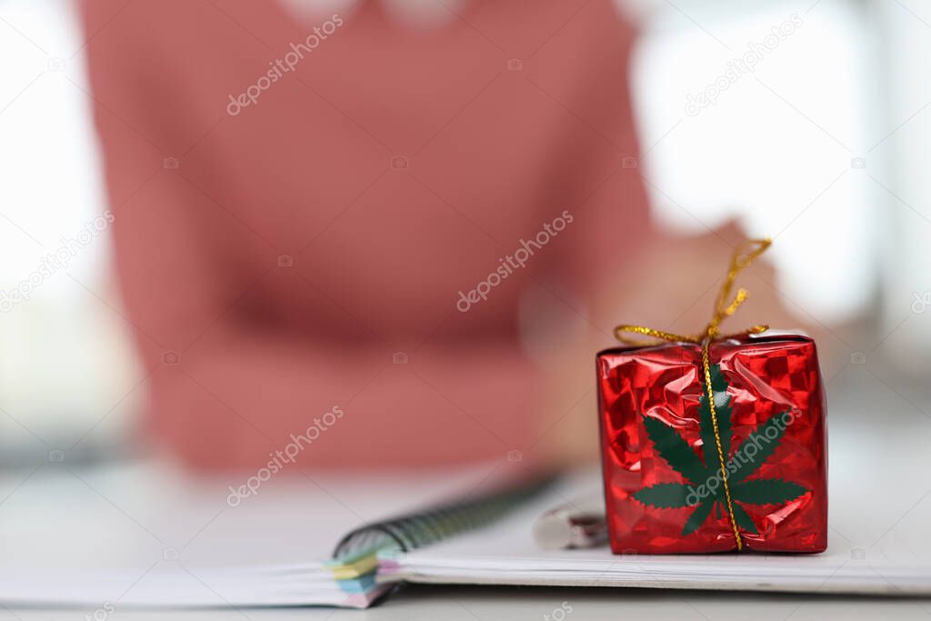 Red gift with marijuana logo on table