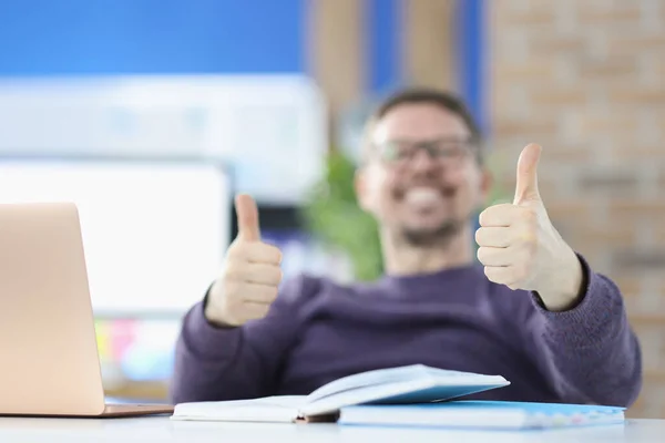 Smiling man showing thumbs up in office closeup