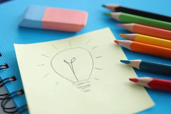 Na folha branca de papel, a lâmpada é desenhada ao lado de lápis e adesivos coloridos — Fotografia de Stock