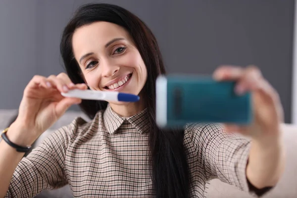 Lachende vrouw toont zwangerschapstest in smartphone — Stockfoto