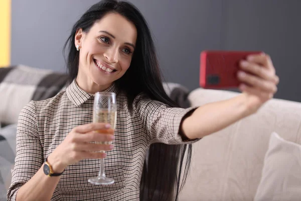Glimlachende vrouw met glas champagne en kijken naar smartphone scherm — Stockfoto