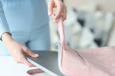 Kadın elleri evde dizüstü bilgisayarı çantaya koyuyor.