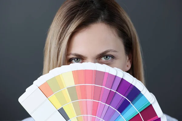 Portrait of woman holding fan of color palette