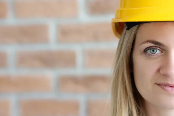 Vrouwelijk portret van bouwer in gele harde hoed tegen muurachtergrond. — Stockfoto