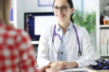 Gözlüklü doktorun gülümseyen portresi hastayla randevu ayarlıyor.