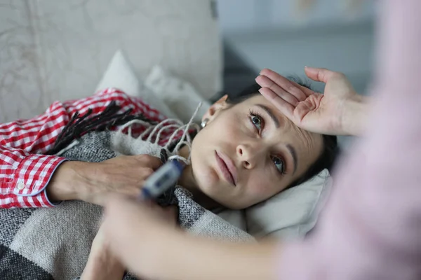Больные женщины температура измеряется на кровати — стоковое фото