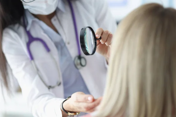 Hautarzt untersucht Gesicht von Patienten durch Lupe — Stockfoto