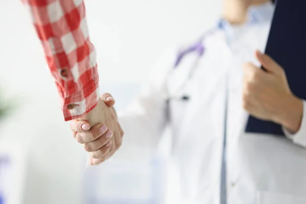 Arzt hält Klemmbrett und schüttelt Patient die Hand — Stockfoto