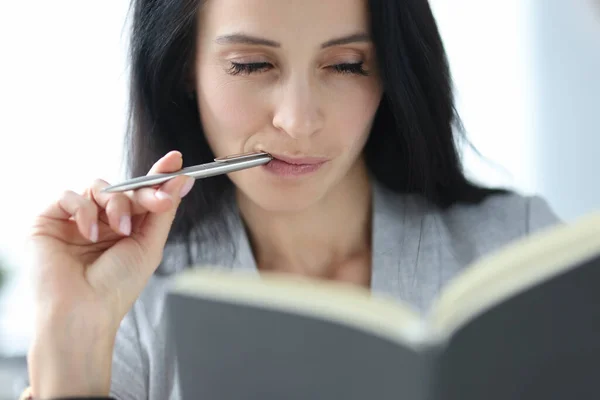 Woman with sly eyes looks at diary — Stock Photo, Image