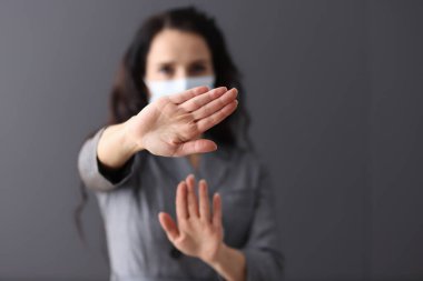 Tıbbi koruyucu maskeli kadın olumsuz bir hareketle ellerini tutuyor.