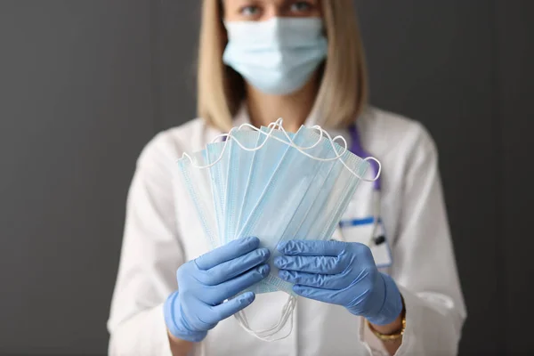 Médico en guantes sostiene máscara médica protectora —  Fotos de Stock