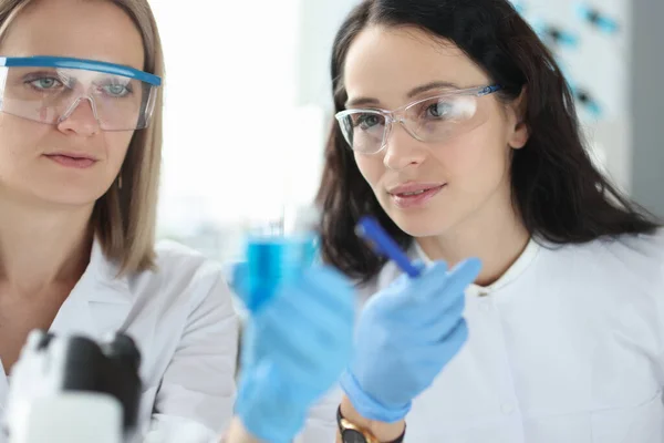 Zwei Wissenschaftler mit Brille betrachten Reagenzglas mit Flüssigkeit. — Stockfoto