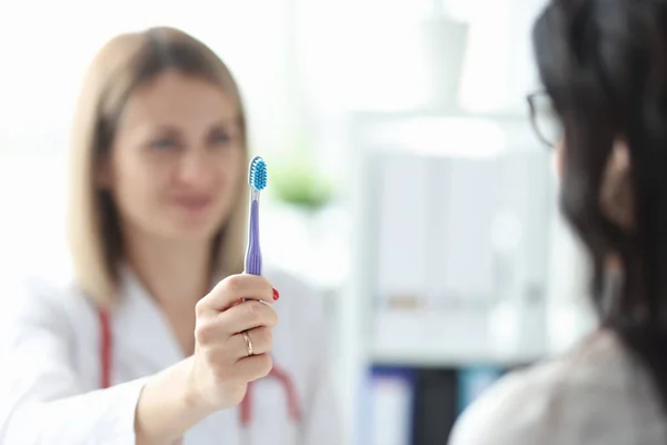 Tandläkaren visar patienten tandborste. Hur man väljer rätt tandborste — Stockfoto