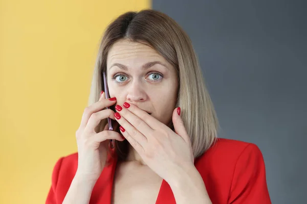 Surprised woman talking on smartphone and covers her mouth with her hand — Stock Photo, Image