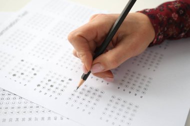 Kadın eli kalemi tutar ve test için cevapları işaretler
